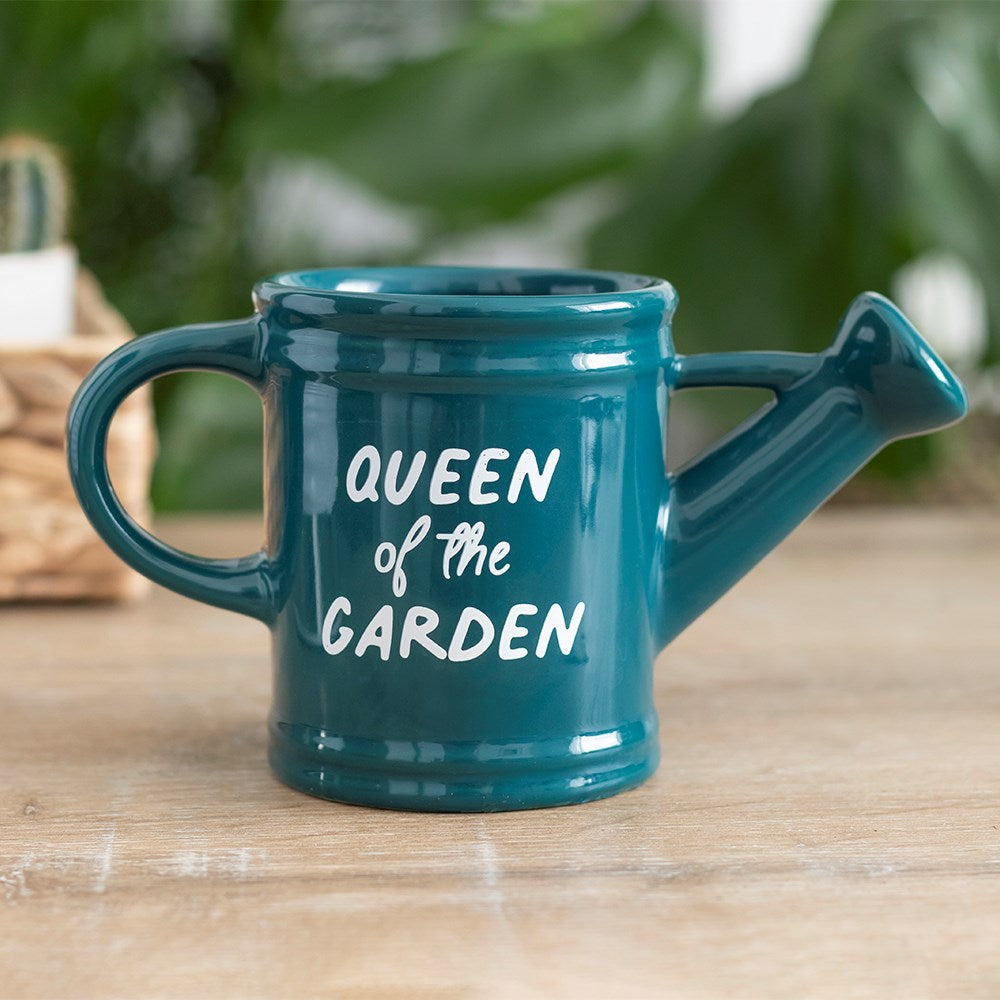 A watering can shaped mug saying Queen of the Garden on the front, sat on a table. Making a great gift for gardening women.